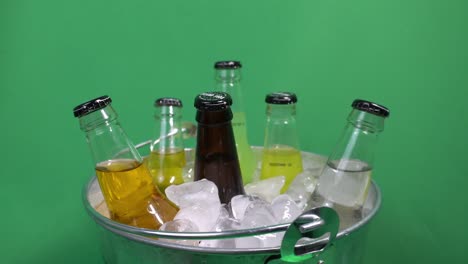 Sortierte-Soda-Glasflaschen-Der-Insel,-Die-Sich-Vor-Einem-Grünen-Bildschirm-In-Einem-Gefüllten-Eiskübel-Mit-Reinen-Natürlichen-Aromen-Drehen,-Die-Mit-Getränken-Der-Marke-Island-Soda-In-Ginger-Beer-Mango-Champagne-Kola-Platzen