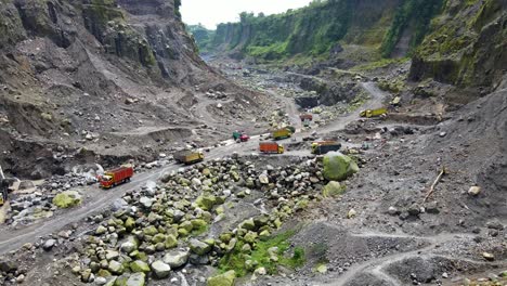 Dump-trucks-transport-output-in-open-pit-mine-near-Magelang,-Indonesia,-aerial