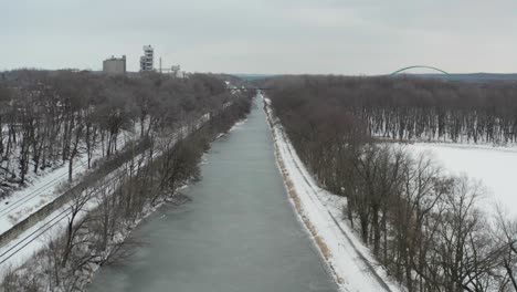 Ascending-over-frozen-river-revealing-city-buildings-in-distance