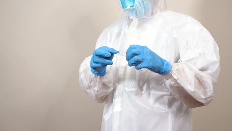 female-doctor-in-ppe-suit-putting-on-gloves-and-sealing-the-suit-with-adhesive
