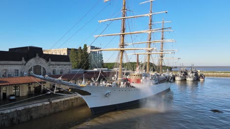 Aerial-pan-left-of-docked-ARA-Libertad-frigate-being-cleaned-in-Puerto-Madero-pier-at-daytime,-Buenos-Aires