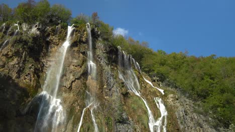 Angled-view-of-the-tall,-thin-waterfalls-of-Veliki-Slap-in-Plitvice-Lakes-National-Park-in-Croatia,-Europe-at-¼-speed