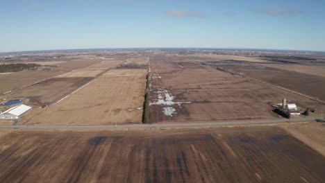 Spring-thaw-on-the-plains-with-brown,-wet-agricultural-fields-below-stretching-for-miles