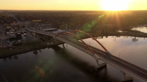 Orbiting-aerial-view-of-Hastings-Bridge-over-Mississippi-River,-as-the-sun-hits-the-distant-horizon