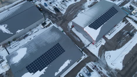 Aerial-of-solar-panels-on-industrial-warehouses-in-winter---drone-lifting-up