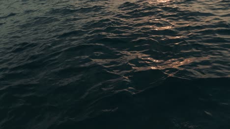 Slow-motion-shot-of-golden-sun-reflecting-during-sunset-in-water-waves-of-blue-ocean