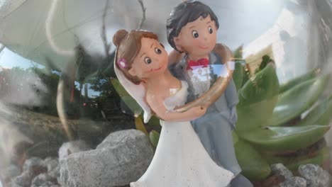 Bride-and-groom-figure-with-wedding-ring-in-a-glas