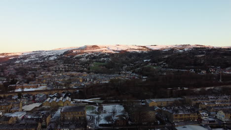 Upward-panning-shot-of-snow-covered-hill-side-glowing-naturally-at-golden-hour