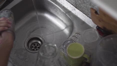 Person-Washing-Glass-WIth-Dishwashing-Soap-And-Water-In-The-Kitchen-Sink---High-Angle-Shot