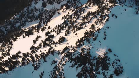 A-high-speed-helicopter-style,-panning-up,-drone-shot-of-a-snowy-peak-in-the-Olympic-mountains-taken-from-just-outside-the-national-park-at-sunset