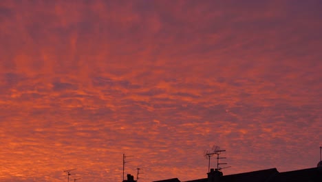 Low-angle-view-of-moving-colorful-clouds-and-silhouette-of-roofs