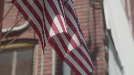 American-flags-on-brick-wall-in-small-town-America,-Slow-Motion