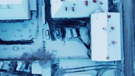 Above-90-degree-angled-drone-shot-of-snowy-buildings,-streets-and-cars