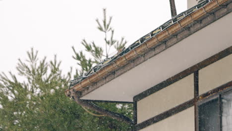 Scene-Of-Snowflakes-Falling-On-House-Roof-During-Daytime-In-Gifu,-Japan