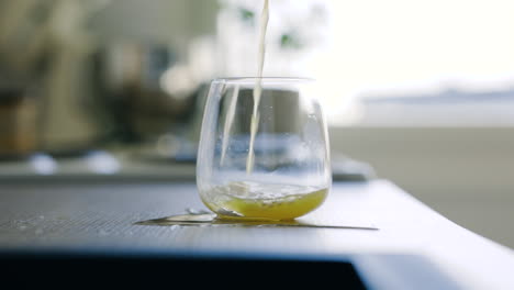 Statische-Slomo-Nahaufnahme-Eines-Gelben-Getränks,-Das-Unbeholfen-In-Ein-Glas-Gegossen-Wird