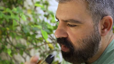Close-up-of-bearded-men-inhaling-e-cigarette-device-in-daylight-01