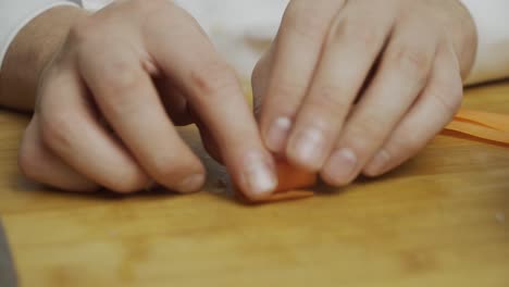 Koch-Rollt-Und-Schneidet-Karottenscheiben-Mit-Küchenmesser-Auf-Holzschnittbrett
