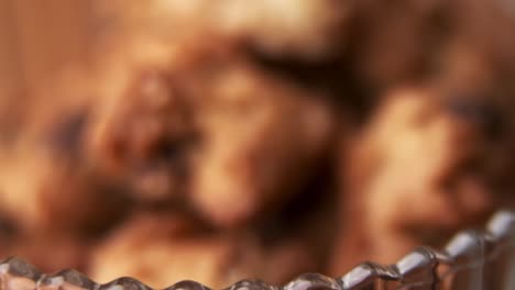 Panning-shot-of-chocolate-chip-biscuits-in-glass-bowl,-pull-focus
