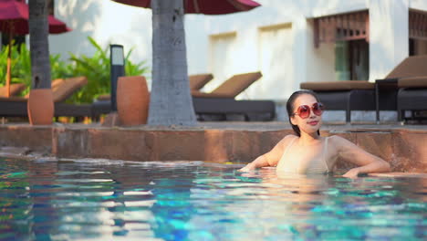 Junge-Asiatin-Mit-Großer-Sonnenbrille-Entspannt-Sich-Im-Pool-Des-Resorts
