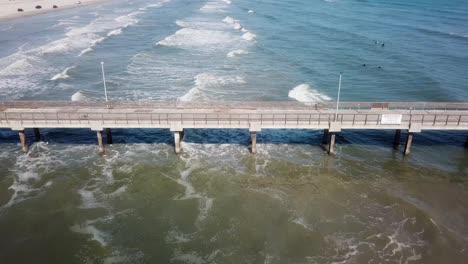 Drone-aerial-view-of-the-Bob-Hall-Pier-and-waves-at-Nueces-County-Coastal-Park-on-North-Padre-Island,-Texas