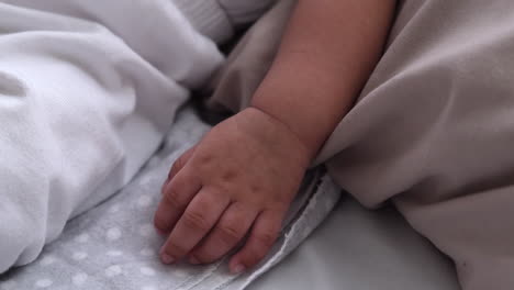 Close-Up-Of-Cute-Baby's-Hand-And-Arm-While-Sleeping-In-Bed