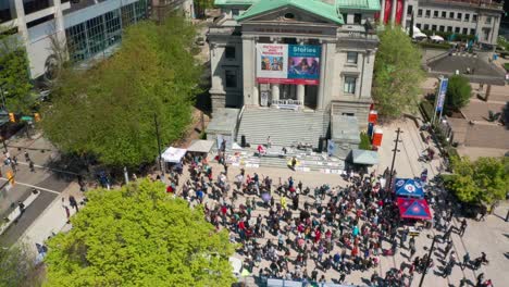 Anti-mask-Protesters-Put-Fists-In-The-Air-at-a-Public-Rally,-Aerial-view-of-Crowd-on-the-Steps-of-the-Vancouver-Art-Gallery-in-Downtown-Vancouver-during-the-2021-COVID-19-Virus-Variant-Lockdowns