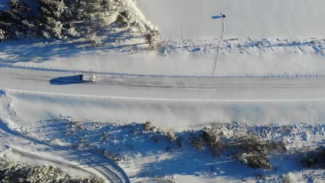 Winterlandschaft-Mit-Einem-Fahrzeug,-Das-Auf-Einer-Schneebedeckten-Straße-In-Der-Nähe-Von-Lappland,-Finnland,-Fährt---Antenne,-Von-Oben-Nach-Unten
