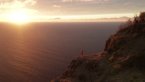 Woman-staring-at-Atlantic-Ocean-from-high-cliff-with-spectacular-vivid-sunset