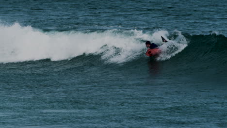 Surfer-enjoying-powerful-ocean-wave-in-distance-view