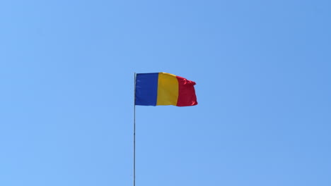 Flag-Of-Romania-On-Flagpole-Fluttering-In-The-Wind-Against-Clear-Blue-Sky