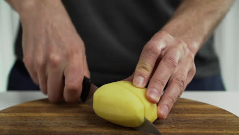 Person-cutting-potato-wedges-on-chopping-board-at-home,-closeup