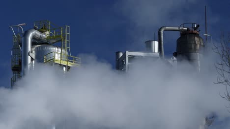 Torre-De-Refinería-Contra-El-Cielo-Azul-Con-Humo-Espeso-Que-Contamina-El-Aire