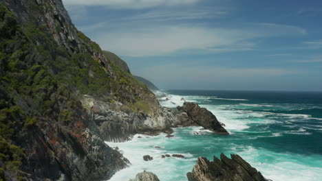 Rocky-Cliff-At-The-Shoreline-Of-Atlantic-Ocean-Under-Cloudy-Blue-Sky-In-Cape-Town,-South-Africa