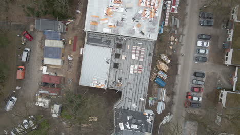 Top-down-Aerial-of-construction-worker-working-under-large-construction-site---drone-setting-down