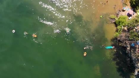 Aerial-over-summertime-activity-on-lake,-people-playing-in-water