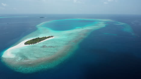 Vista-Aérea-De-Una-Hermosa-Isla-Pequeña-En-Las-Maldivas-Con-Palmeras-Verdes-En-Agua-Azul