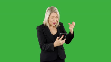 Attraktive-Blonde-Geschäftsfrau,-Die-Wütend-Und-Verärgert-Ist,-Als-Sie-Mit-Einer-Spiele-App-Auf-Ihrem-Telefon-Mit-Grünem-Hintergrund-Geld-Verliert
