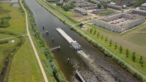 Aerial-drone-view-of-the-epic-scene-big-shipping-ship-or-boat-passing-at-the-canal-in-the-Netherlands