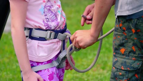 Safety-harness-fall-protection-set-on-a-little-girl-in-pink-t-shirt