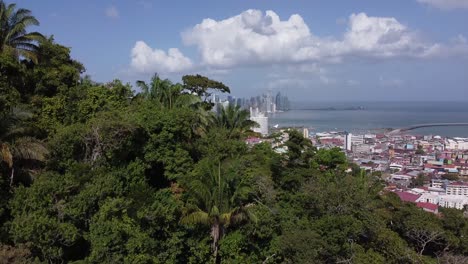 Aerial-climbs-lush-jungle-on-Ancon-Hill-to-reveal-downtown,-Panama-City