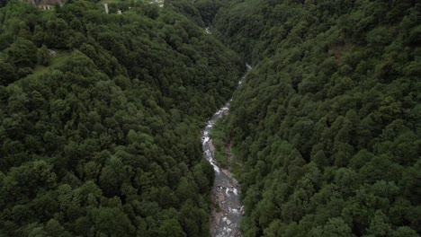 Río-Natural-Remoto-Que-Fluye-A-Través-De-Un-Valle-Forestal,-Pequeña-Iglesia-En-La-Colina