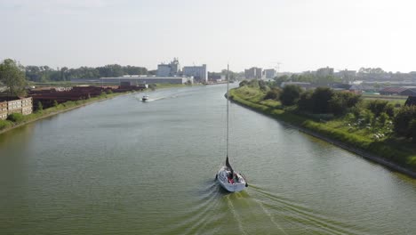 Tracking-shot-of-a-sailboat-on-the-Canal-through-Walcheren-in-Zeeland,-the-Netherlands,-on-a-sunny-summer-evening