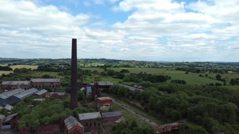Abandoned-old-overgrown-coal-mine-industrial-museum-buildings-aerial-dolly-left-countryside-view