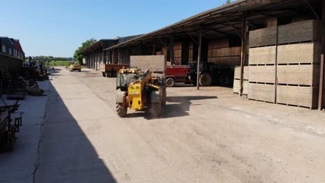 JCB-machine-carrying-bins-for-potatoes-across-a-Kent-farmyard