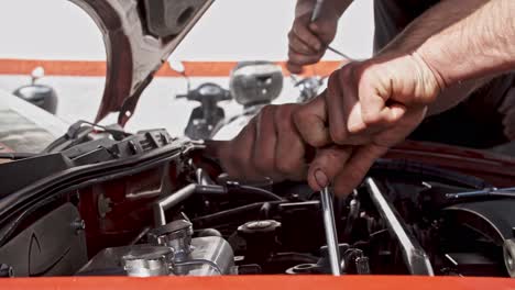 Strong-man-using-wrench-to-fix-car-engine-in-close-up-view
