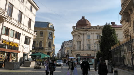 Gente-Con-Máscaras-Caminando-Por-La-Calle-En-El-Casco-Antiguo,-Bucarest,-Rumania-Durante-La-Pandemia-Con-El-Edificio-Del-Gobierno-En-Segundo-Plano