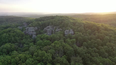 Majestic-hill-covered-in-forest-with-rocky-cliff-with-sunshine,-drone-orbit