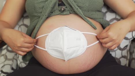 A-young-pregnant-woman-places-a-mask-on-her-belly