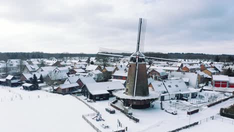 Drone-over-Dutch-winter-windmill-covered-in-snow,-all-covered-under-ice-during-extreme-winters