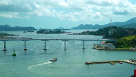 Fishing-Boat-Sailing-Across-The-Geoje-Bridge-With-Traffic-In-Geojedo-Island,-South-Korea